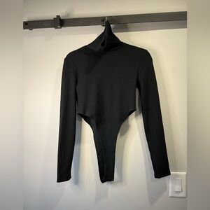Turtle neck ribbed black high cut body suit, size small. Gently worn once